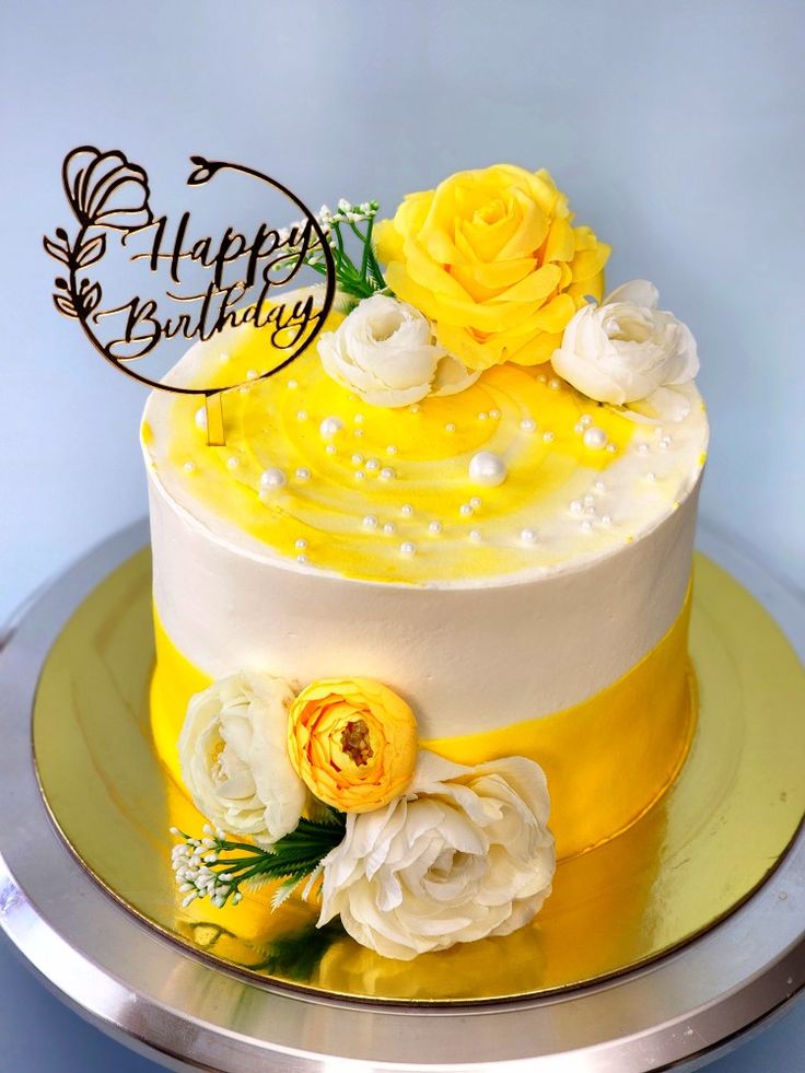 there is a yellow and white cake with flowers on the top, it says happy birthday