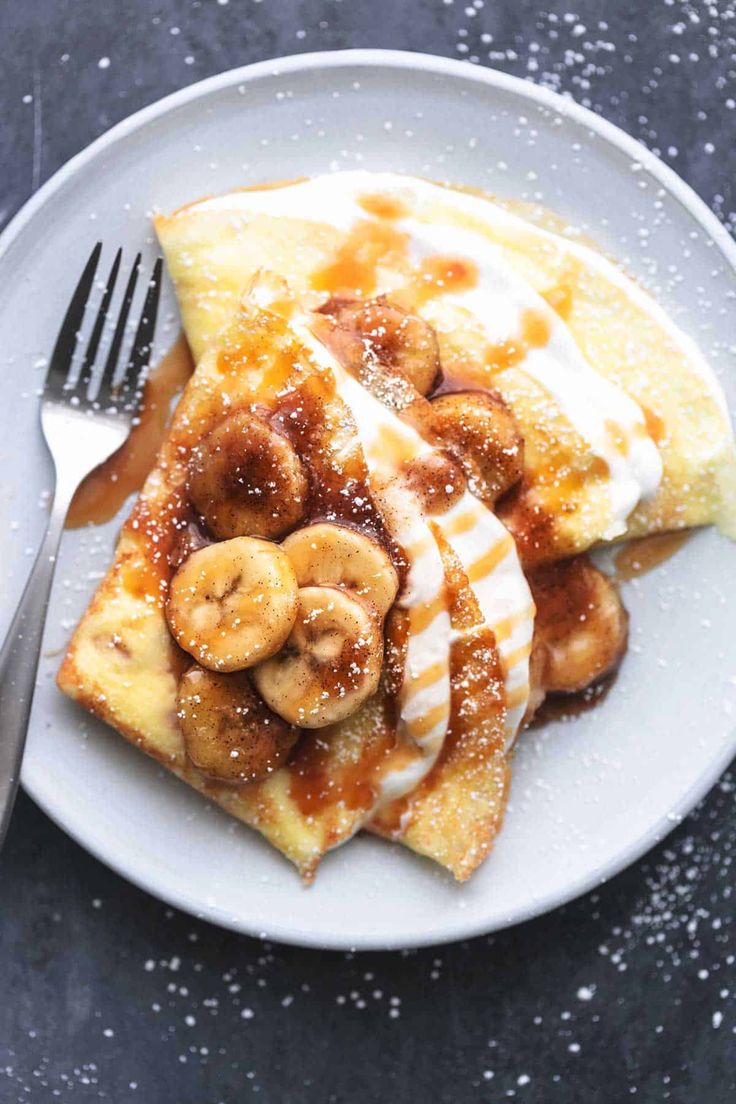 a white plate topped with waffles covered in syrup and bananas next to a fork