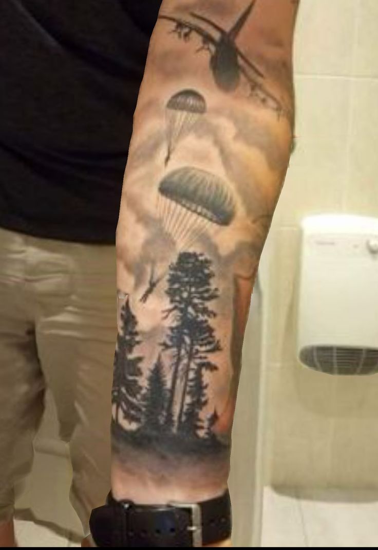 a man's arm with an airplane and trees on it