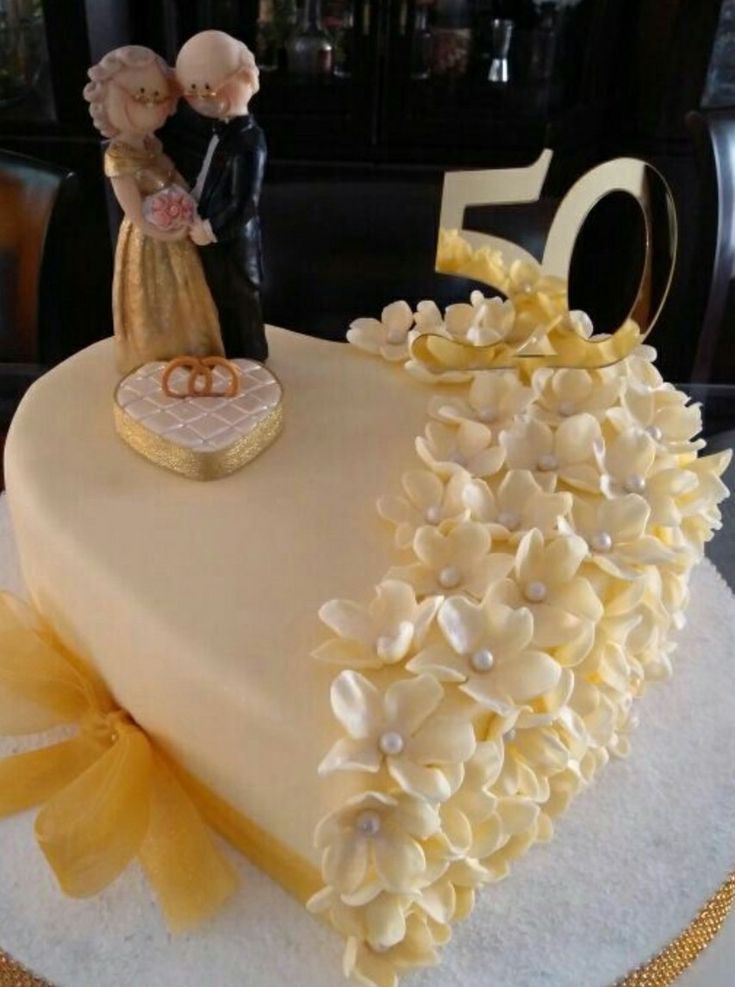 a 50th cake decorated with flowers and a figurine in the shape of a heart