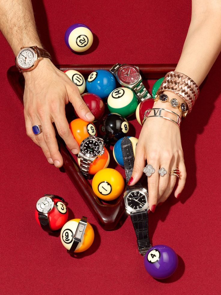 two hands reaching for pool balls in a pool table