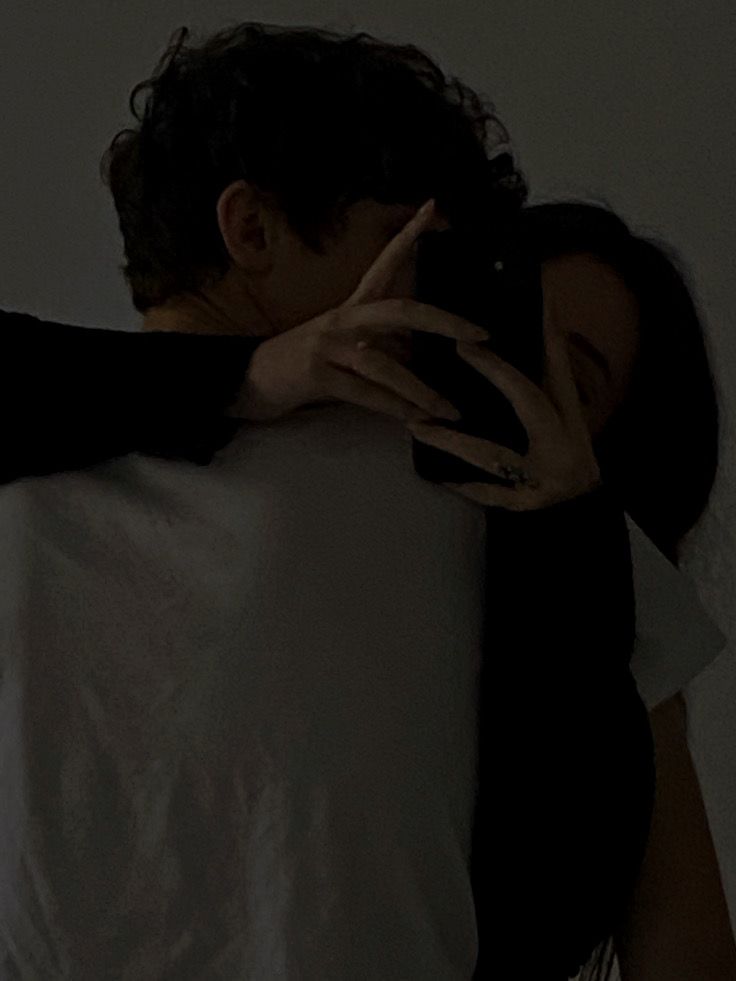 two people hugging each other in the dark