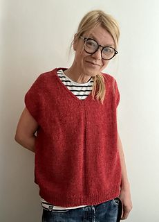 a woman wearing glasses standing in front of a white wall with her hands on her hips