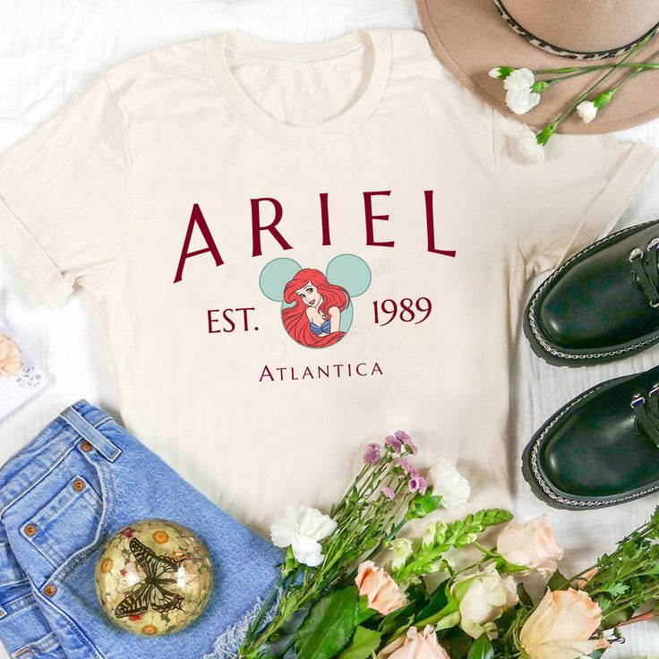 the ariel shirt is next to some flowers and shoes