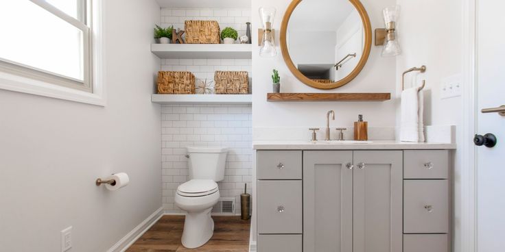 a white toilet sitting under a bathroom mirror next to a wooden counter top and sink