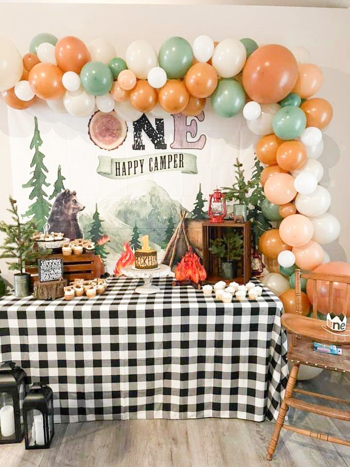 a table topped with lots of balloons and desserts next to a sign that says no happy camper