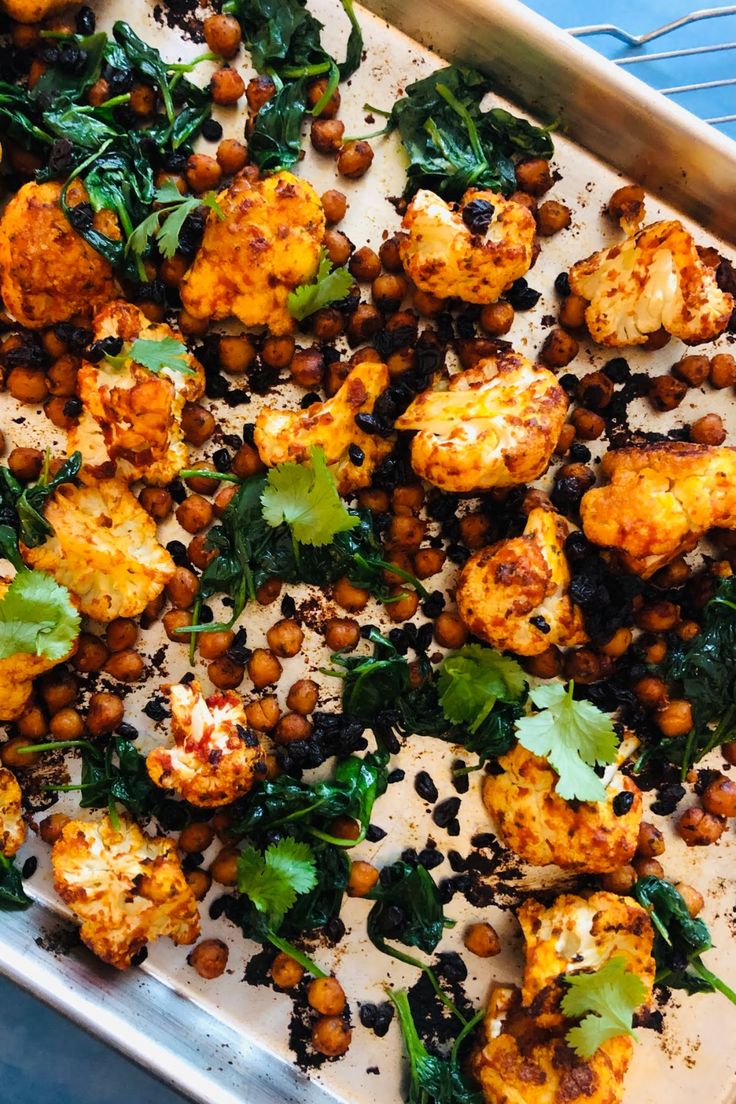 cauliflower, chickpeas and greens on a baking sheet in a pan