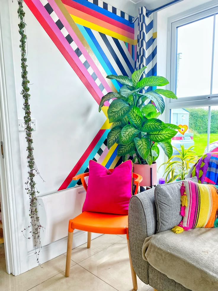 a living room filled with lots of colorful furniture next to a large potted plant