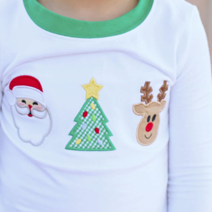 These Christmas Cheer Pajamas will have your little one ready for Christmas morning! The white long sleeve pajama top features our classic Christmas appliqués, including Santa, a Christmas tree, and a reindeer. The set includes red stripe pajama bottoms with green ribbing. Add a monogram to personalize your Christmas look. Designed to be snug-fitting. Please check the Size Chart for measurements and order accordingly. White Long Sleeve Christmas Sleepwear, White Long Sleeve Sleepwear For Christmas, White Long Sleeve Sets For Holiday, White Long Sleeve Holiday Sets, White Long-sleeve Holiday Sets, Cotton Christmas Bedtime Tops, Christmas Cotton Bedtime Tops, White Long Sleeve Christmas Sets, Festive White Long Sleeve Sleepwear