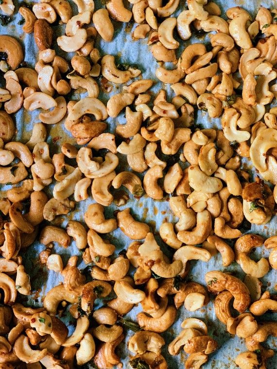 a bunch of cashews are on a sheet of tin foil and ready to be eaten