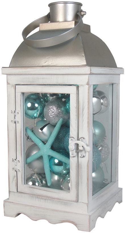 a lantern with ornaments in it and a starfish on the top, sitting next to each other