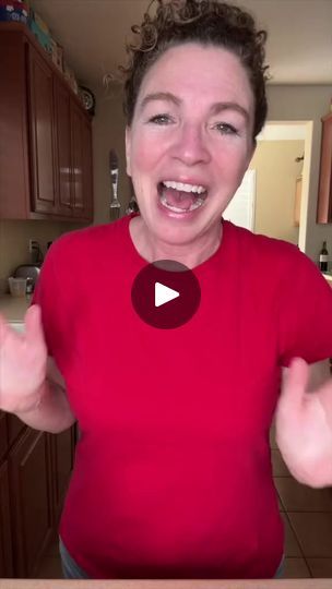 a woman in a red shirt is holding her hands up and making a funny face