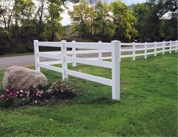 a white fence with flowers and rocks in the grass