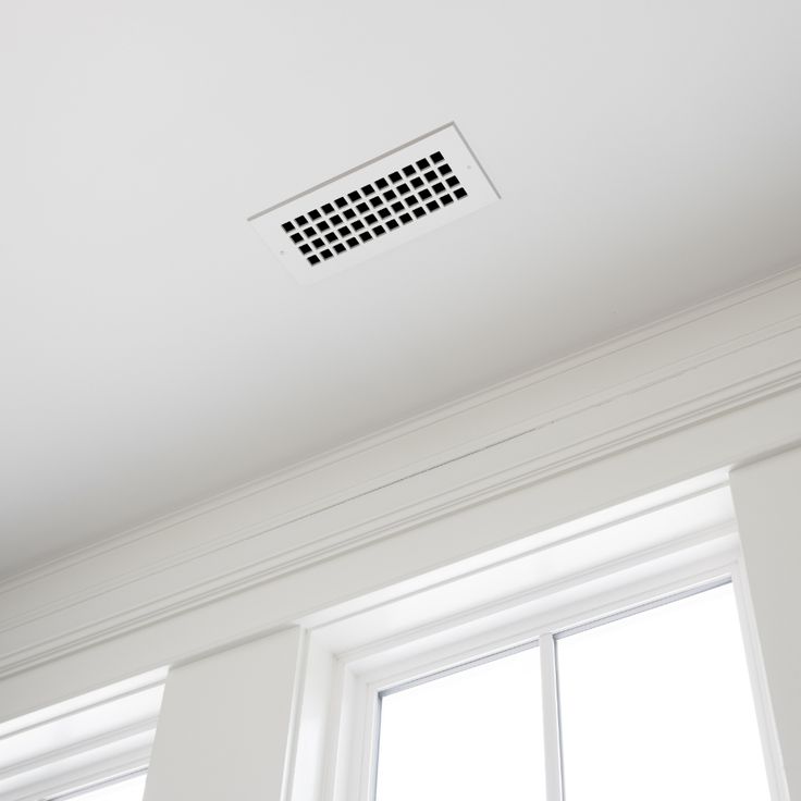 a white ceiling with a vent on it and two windows in the back ground area