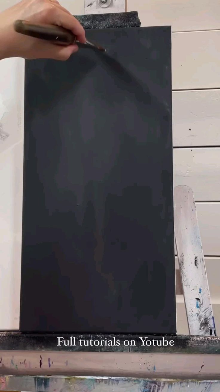 a person is painting a black piece of art