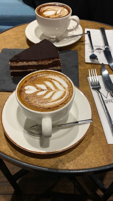 there is a cup of coffee on the table with silverware and spoons next to it