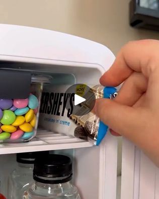 a person is opening the door to a mini fridge filled with candy and candies