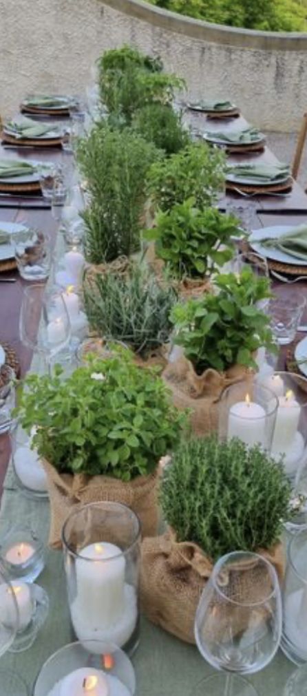 an outdoor table set with candles, plates and plants in burlap sack bags