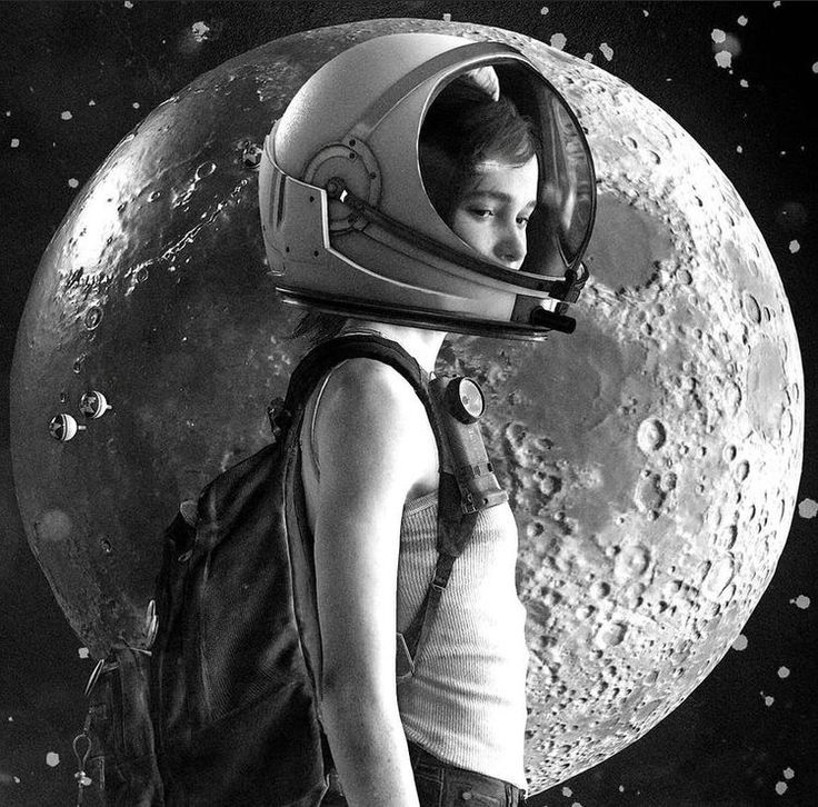 a woman wearing an astronaut's helmet standing in front of the moon