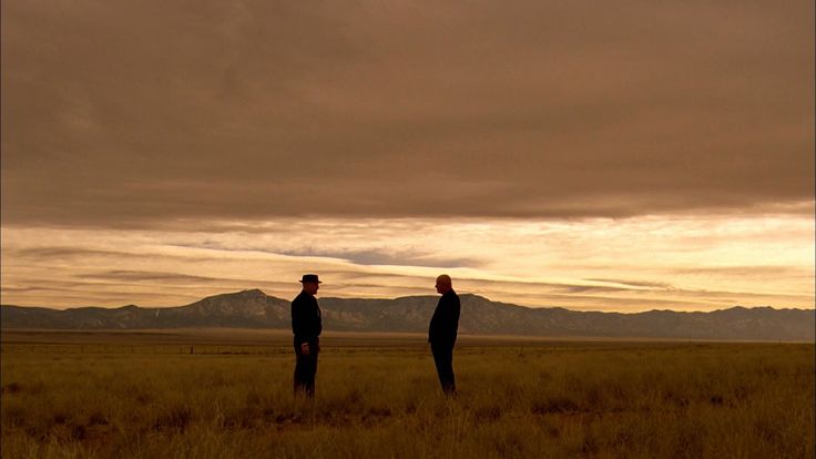 two men standing in the middle of an open field