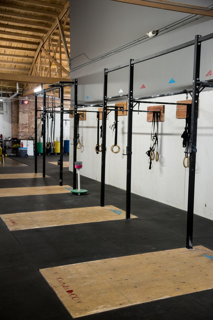 the inside of a gym with ropes and rings hanging from the ceiling, in front of other equipment