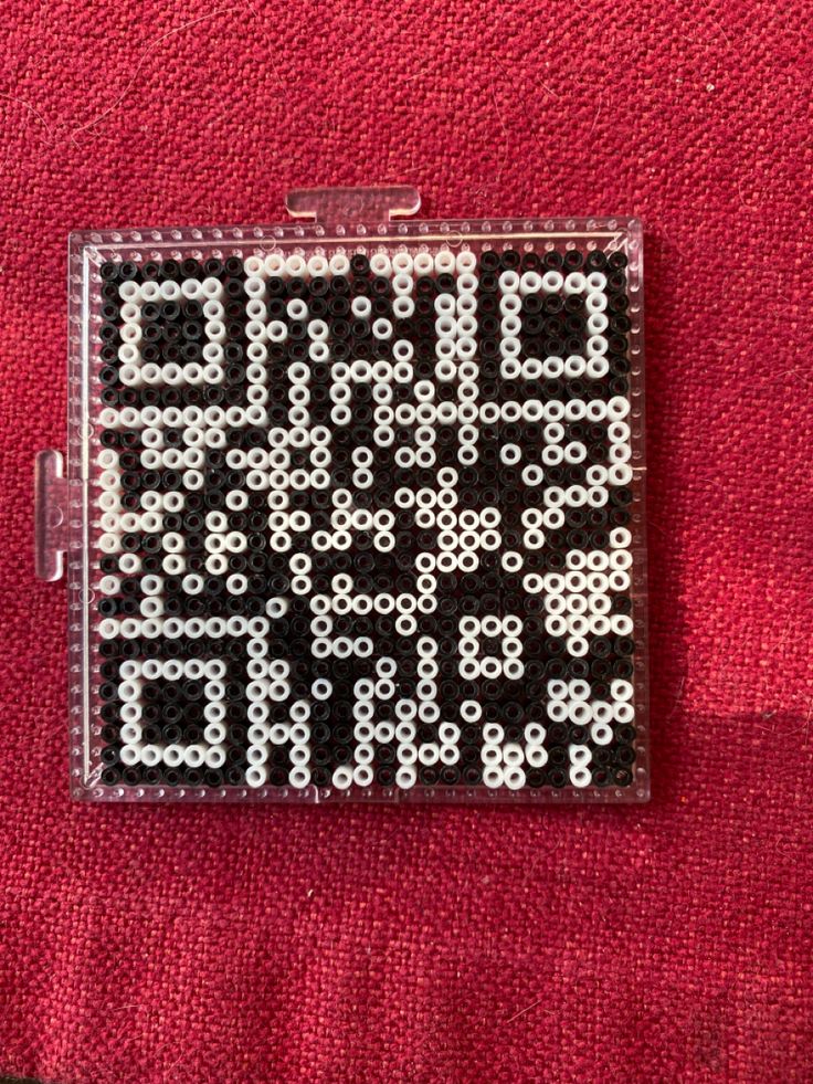 a piece of black and white bead art on a red cloth with the words end game written across it