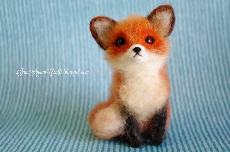 a small stuffed fox sitting on top of a blue blanket