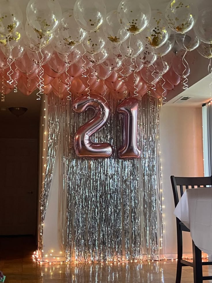 balloons and streamers are hanging from the ceiling in front of a number twenty sign