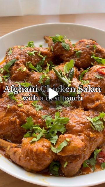 a white bowl filled with meat and garnished with cilantro leaves on top