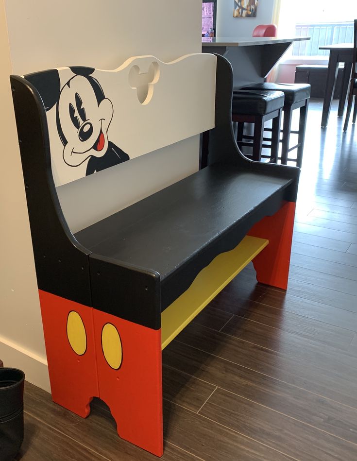 a child's wooden bench with mickey mouse painted on the back and side panels