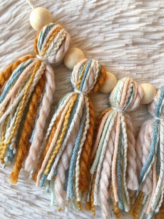 multicolored yarn tassels with wooden beads on a white cloth covered surface