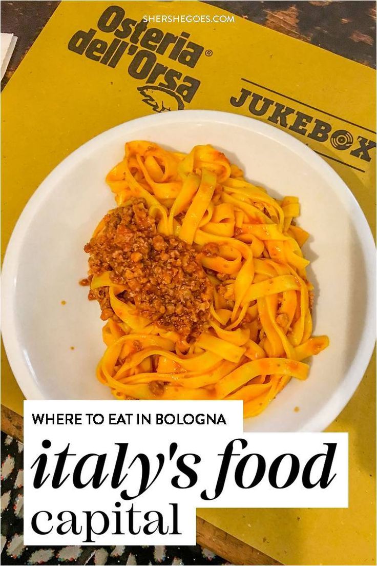 a white bowl filled with pasta sitting on top of a wooden table next to a yellow sign