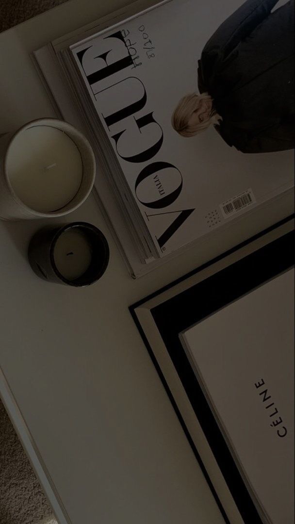 an image of a magazine on a table with candles and a cup next to it