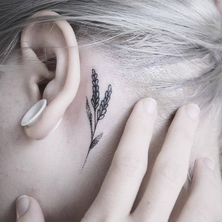 a close up of a person with a tattoo on their ear and behind her ear is a flower