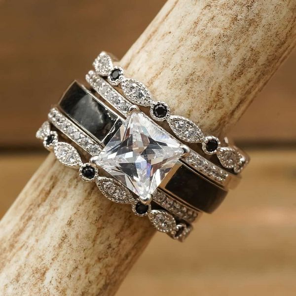 a ring with black and white stones on it sitting on top of a wooden stick