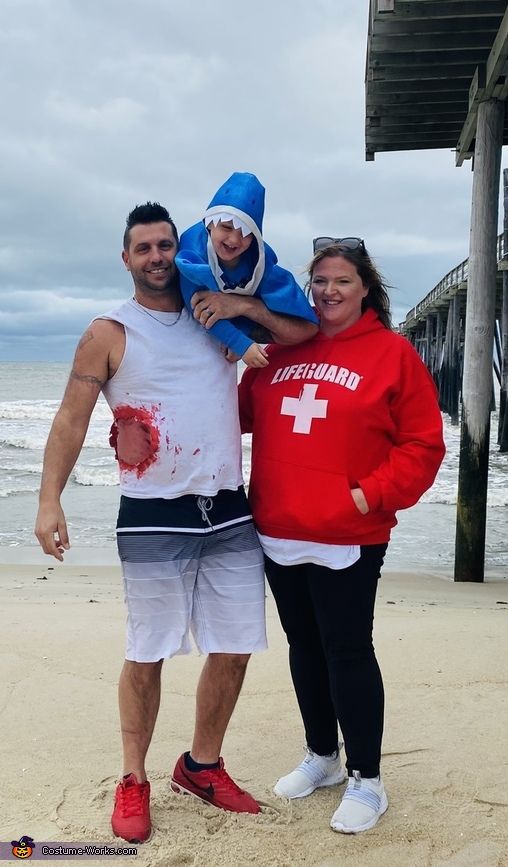 two men and a woman standing on the beach with blood all over their bodys