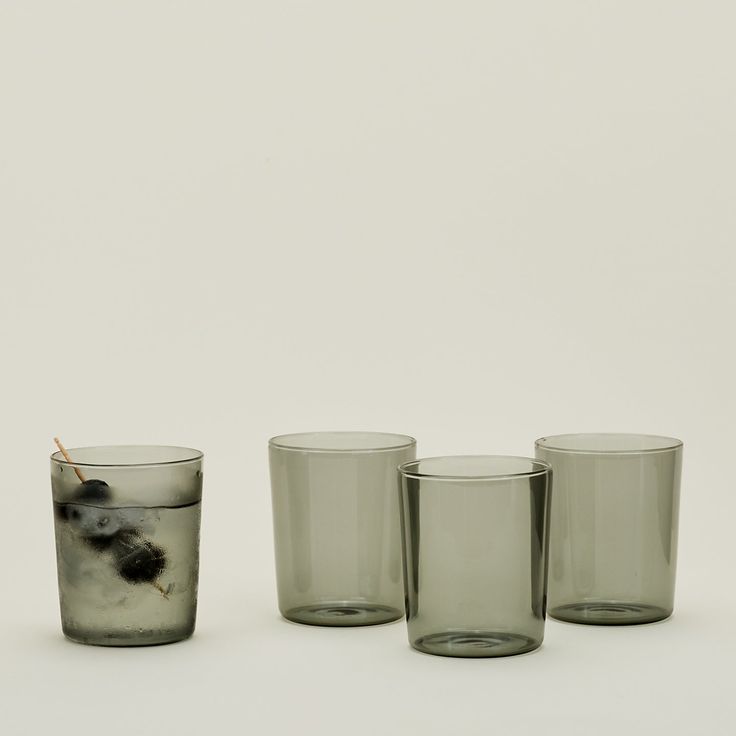 three glasses with one filled with liquid and the other empty, on a white surface