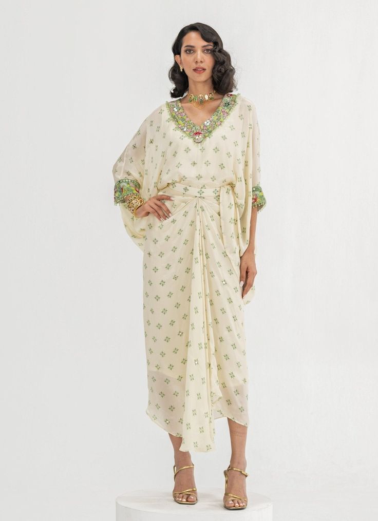 This elegant Ivory Embroidered Toga Cape Skirt Set is a timeless blend of sophistication and comfort. Crafted from soft crepe fabric, the set features a Ivory-colored, loose-fitting cape adorned with intricate floral embroidery around the neckline and cuffs. Paired with a wrap-style skirt that accentuates the waist and drapes effortlessly, it creates a flattering fit while ensuring easy movement. Ideal Indo-Western attire for home poojas, family gatherings, or festive occasions. Composition : Top and Skirt - Crepe Care: Dry Clean Only and Vacuum Storage This product can be customized for sleeves, blouse length and neckline Delivery : 4-6 weeks as the product is hand crafted. Check Size Guide or choose MySize for free customisation (All Sizes above XL can be made at 15% additional cost) For Cape Skirt, Indo Western Dresses For Women, Vacuum Storage, Indo Western Dress, Indian Wedding Wear, Sleeves Blouse, Indo Western, Top And Skirt, Style Skirt