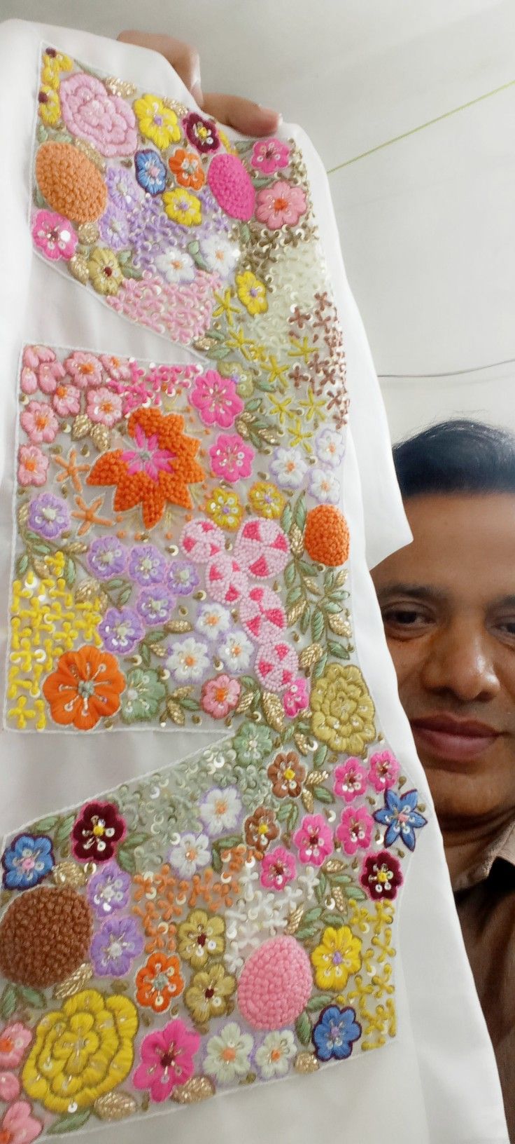 a man holding up a piece of fabric with flowers on it and sequins