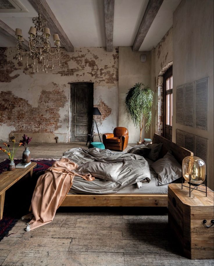 an old bedroom with exposed brick walls and wooden bed frame in the middle, along with a chandelier hanging from the ceiling