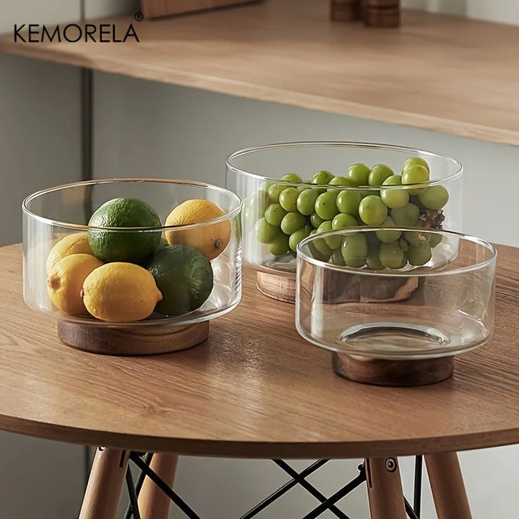 two clear bowls filled with fruit sitting on top of a wooden table next to each other