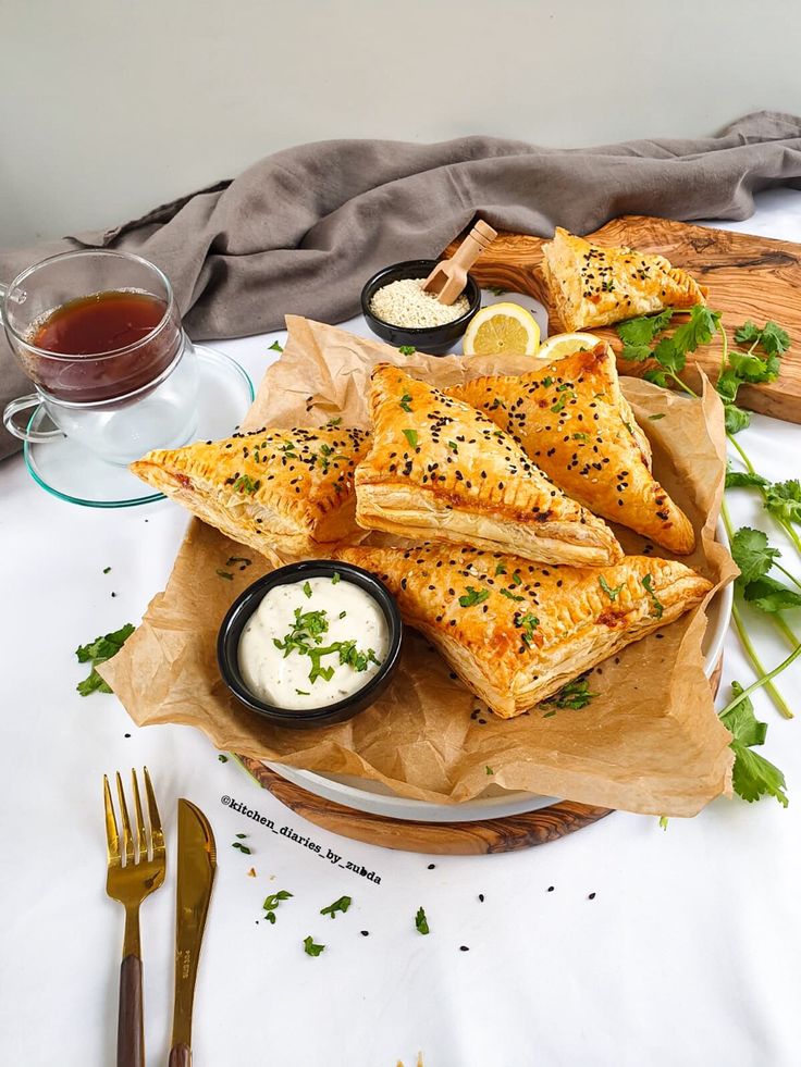 some food is sitting on a plate with dipping sauces and a glass of tea