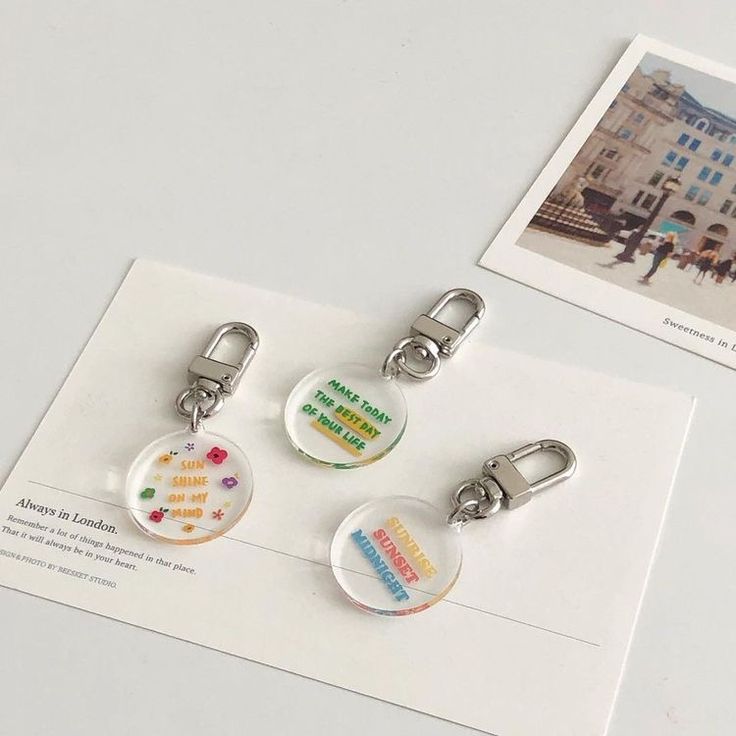 three key chains with different designs on them sitting on top of a piece of paper