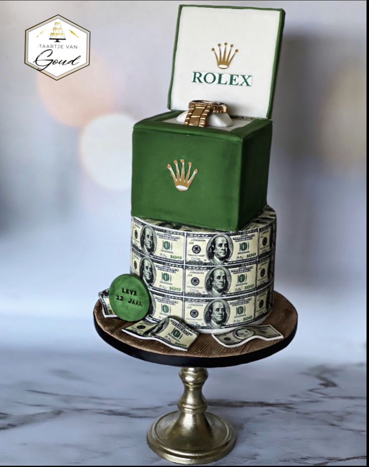 a cake made to look like a stack of money with a rolex box on top