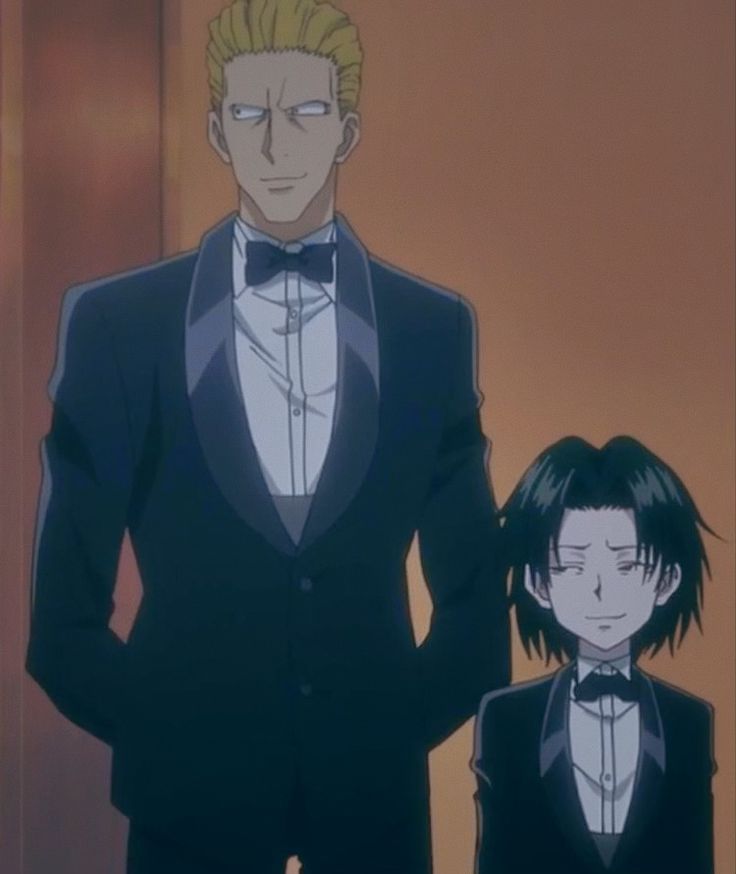 two people in tuxedos standing next to each other with their hands on their hipss