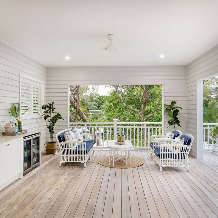 an outdoor living area with white furniture and wood flooring