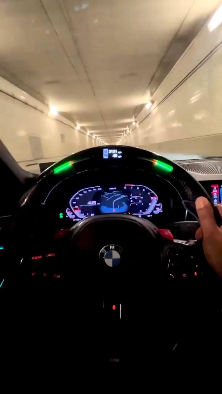 a person driving a car in a parking garage with the dashboard illuminated green and white