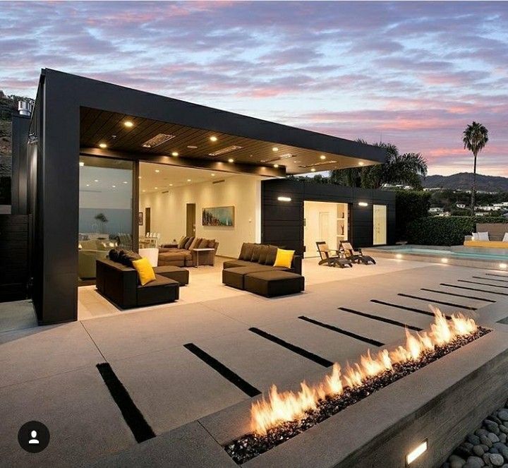 an outdoor fire pit in front of a modern home