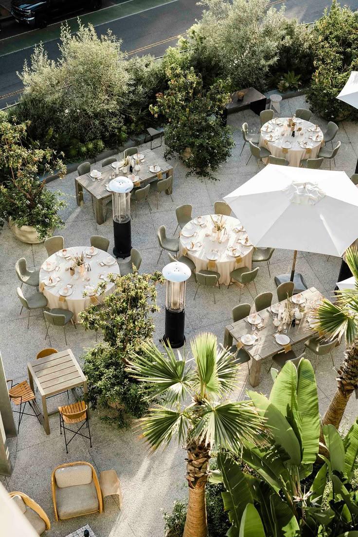 an overhead view of tables and chairs with umbrellas on the ground near palm trees