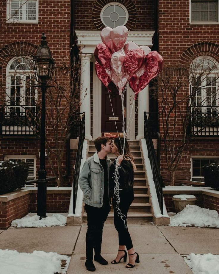 a man and woman standing in front of a building with balloons attached to their heads